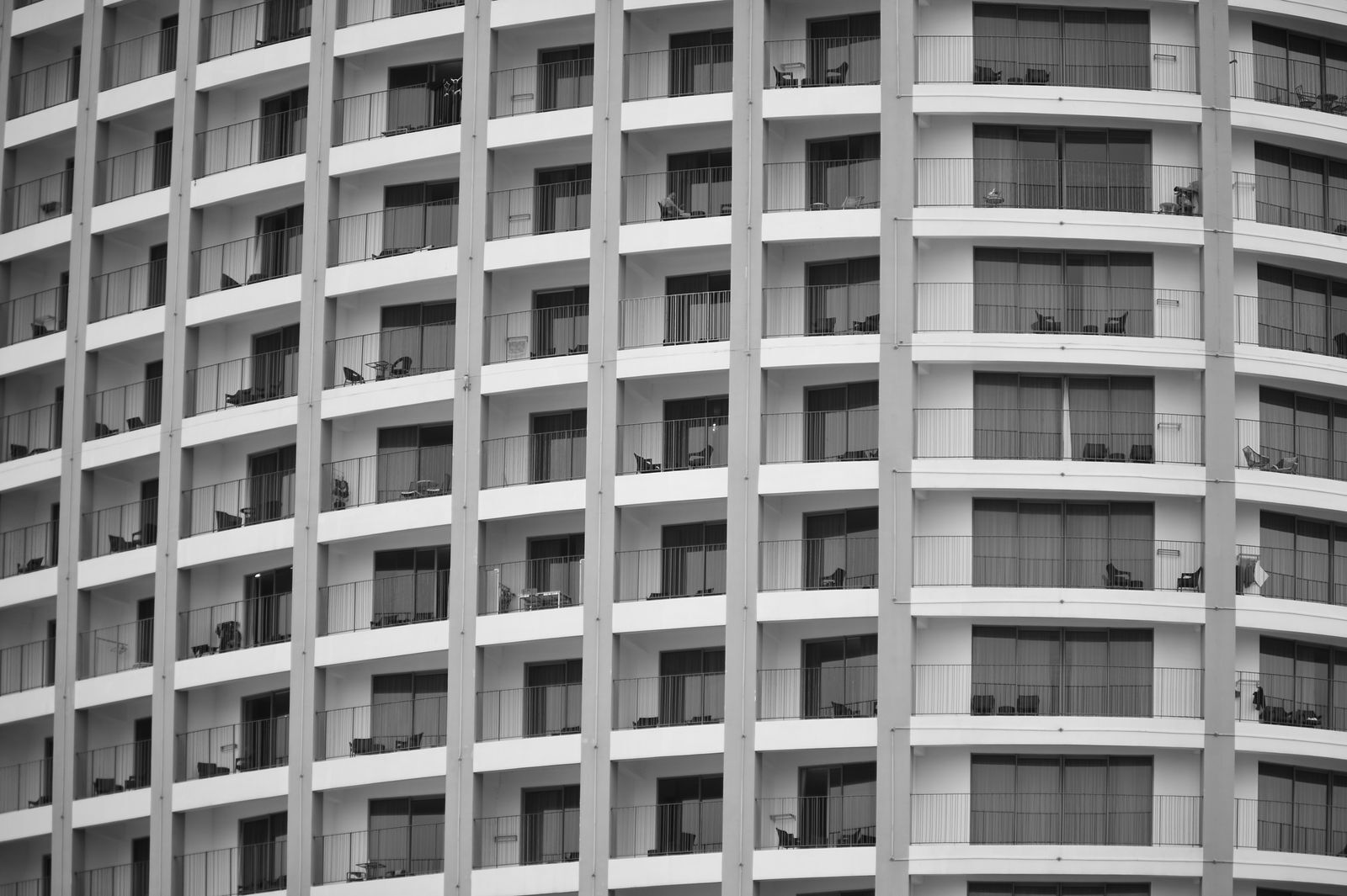 The curved facade of an apartment building, with rows of identical balconies
