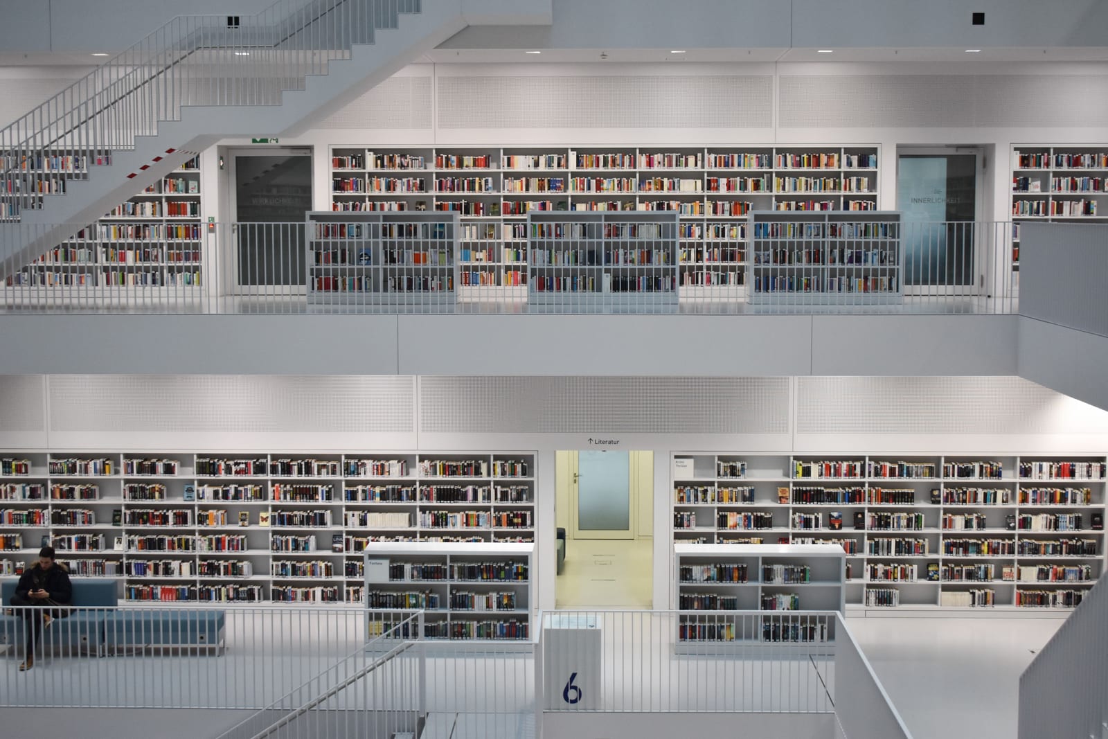 Multi-level library interior with white walls and shelves of books on every floor